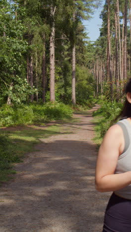 Vertical-Video-Of-Couple-Exercising-Doing-Work-Out-Outdoors-Running-Along-Track-Through-Forest-Towards-Camera-Wearing-Sports-Clothing-Shot-In-Real-Time-1